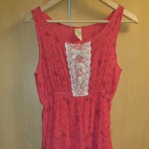 Rosa klänning Strl. L - Jättegullig rosa klänning med små blommor och spets I Strl. S. Köpt på affären Vanilla Vintage i Thailand. Asgullig klänning i bra kvalitet. Endast använd någon enstaka gång. Tyget är ej stretchigt men det är resår i midjan. Passar troligen S-L då det är asiatisk storlek. Priset kan diskuteras. Skickas mot fraktkostnad.