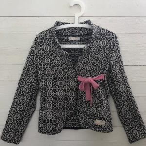 Odd Molly kofta strl 0 - Odd Molly lovely knit jacket i färgen svart/vit med rosa band och detaljer. Strl 0, vilket ungefär motsvarar XS. Nypris 1595kr. Köparen står för frakt. 