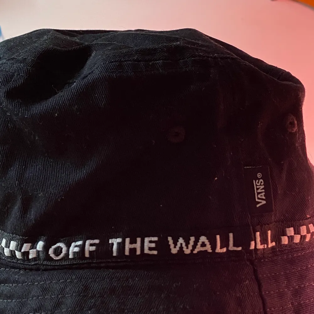 En svart bucket hat från vans med texten ”off the Wall” runt hela. Den har även en liten detalj på insidan som ni ser på andra bilden . Övrigt.