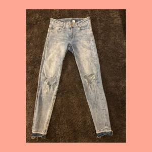 Jeans med hål - Ljusblåa jeans med hål i knäna. Från H&M i storlek 34. Använda i gott skick. Pris: 40kr +frakt🚚