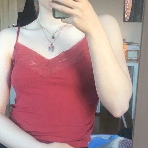 Gulligt linne med spets och v-hals! XS - Ett jättefint rött/rosarött linne med spets runt kragen i XS! Pris: 40kr