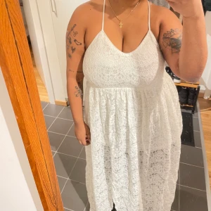 Vit maxiklänning i spets från Nelly - Aldrig använd. Gott skick. Jag är 157 cm och klänningen släpar nästan i golvet när jag har på mig den.