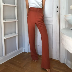  - Kostymliknande byxor i färgen rostbrun/orange, något bootcut. De är för stora och långa för mig, så sitter säkert mycket snyggare på någon som är större. (Drar åt dom lite i rumpan på bilden😀).