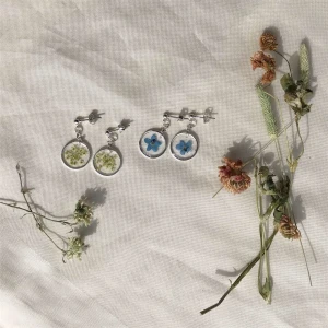 Örhängen av resin och pressade blommor! - NU!! Två par örhängen av resin och blommor jag plockat och pressat själv. Silverfärgad metall. Kan fås med clips om så önskas!! De blå är med förgätmigej och de vita är körvel. 75kr/par, fri frakt. Jag ansvarar inte för postens slarv. 