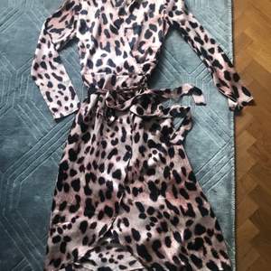 Vacker helt oanvänd Omlottklänning i ljusrosa Leo-print från dancing leopard. Eftersom det är en omlottklänning så passar den både en small och medium men är en uk strl 10 och svensk 38. 