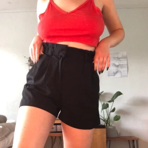 Svarta shorts  - Ett par shorts med kostymbyxliknande tyg. Väldigt svala och sköna! De är väldigt vida i benen och med resor och plats för skärp i midjan. Knäppe se tredje bilden! Varsamt använda och därmed i bra skick. Frakt tillkommer🌺
