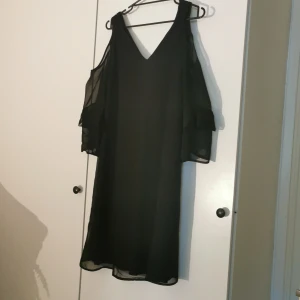 Svart klänning öppen axel stl 36. - Svart snygg klänning med öppen axel och halvlång ärm. Helt ny. Stl 36. Köpare står för frakt. 