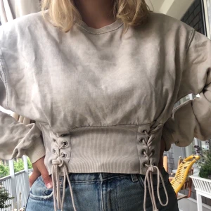 Collegetröja med korsett - Superskön tröja från Pull & Bear i strl small. Knappt använd. Jättefin rosa färg med grålila toner. Korsettdetaljen knyter man själv så den kan sitta både tight och löst👏🏼 köparen står för frakt💕