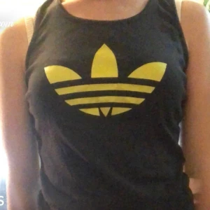 Adidas linne - Ett svart adidas linne med neon tryck. Använd fåtal gånger och är i bra skick. Kan mötas upp i Ängelholm och frakta köparen står för frakt. BUDA!!!