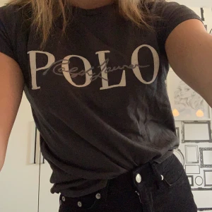 Ralph Lauren  - En svart/grå t-shirt med en vit och grå text där det står ”Polo Ralph Lauren” från Ralph Lauren, knappt använd!! Storlek XS