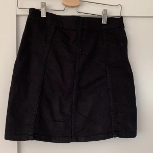 Svart jeanskjol - Kjolen är i super skick har bara använt kjolen en sommar köpte den sommaren 2019💗 kjolen sitter snyggt i passform och sitter bra i längden💗 jag skulle beskriva kjolen som en svart jeanskjol med svarta knappar, storleken på kjolen är 36💗 