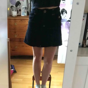  - Svart kjol i Manchestertyg med fickor och gulddetaljer 