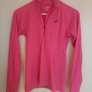 Asics träningströja XS - Rosa Asics träningströja med halvzip och lite högre krage (ändå inte helpolo skulle jag säga). Har en liten ficka i nedre kanten på ryggen (se bild 3) och hål för tummarna vid ärmslut.  Storlek XS, passar även S om man vill att den sitter lite tightare.