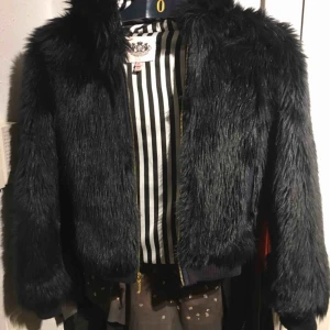  - Jättefin jacka som dottern använt vid fest i svart fuskpäls. Som nyskick ! Stl 12 år men eftersom den har muddar kan flickan ha den från 10 år.