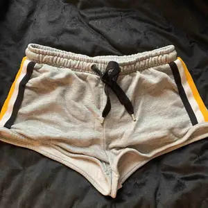 Grå mjukisshorts från Bershka med detaljer av svart, gult och vitt i storlek S. Bra skick! Tillkommer frakt på 44kr