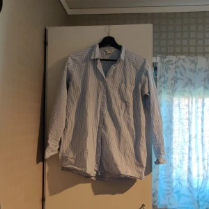 Randig skjorta i bomull, strl XS - Löst sittande skjorta (jag har strl L och kan ha den) från Monki. Använd flera gånger men är hel och skakar fläckar eller liknande. Bröstficka på ena sidan. Kan skickas, då betalar köparen för frakten (priset kan diskuteras).