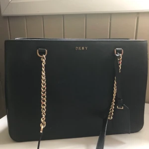 DKNY väska - Väska från DKNY, svart med gulddetaljer. Använd men i bra skick. Köpt för 1800