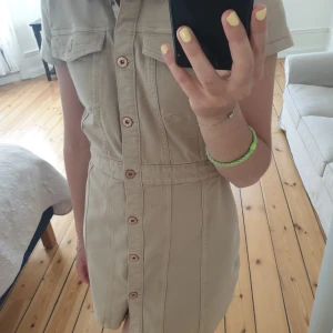 Jeans klänning - Säljer en beige jeansklänning från HM, aldrig använd så helt felfri. Väldigt fin och härlig till sommaren. Jag är 173 cm lång 
