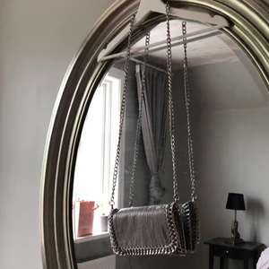 Ljusgrå kedjeväska - Ljusgrå crossbodybag. Väskan har en silvrig avtagbar kedja och kommer ifrån scorett. I läder imitation. Tidigare vikte jag in kedjan och använde den som en axelremsväska, den är perfekt för de nödvändigaste när man ska ner på stan. Bra skick. Nypris 450.