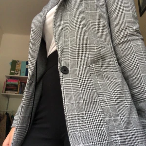 Grå kavaj - Mönstrad kavaj, endast använd en gång. Lent material och stora fickor! Frakt ingår.