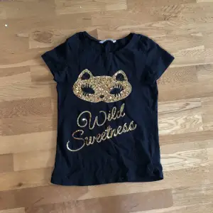 Snygg T-shirt från H&M. Använd fåtal gånger och i väldeligt bra skick. Paljetter på framsidan med texten ”Wild Sweetness”. 