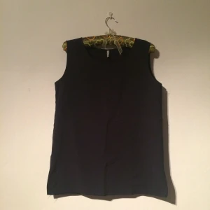  - Mörkblått linne/blus i finare tyg med ett fint broderi på bröstet. Köpt second hand och knappt använd. Frakt tillkommer. 