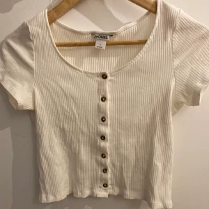 Ribbad, vit topp - Supergullig vit topp med knappar 🔥 Köpt på Monki för ett par år sedan ⭐️ Den är lite kortare i modellen (nästan croptop 🤷‍♀️), jättefint skick! ✨ Går självklart knäppa upp knapparna ⚡️ Köparen står för frakt, hör av er vid frågor/fler bilder 😊