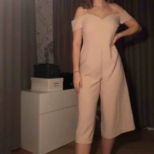  - Superfin formsydd ljusrosa jumpsuit från River Island. (Ser mer beige ut på bild men är ljusrosa/puderrosa) Endast använd 1 gång och inköpt för 699kr. Passar perfekt till fest, bröllop osv. Benen är i kort och vid culotte-modell. I perfekt skick.