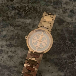  - Damklocka från Tory Burch i guld med vit urtavla, mycket fint skick!!! Nypris 3500kr. Finns extra delar för att reglera storleken på armbandet som medföljer klockan. 