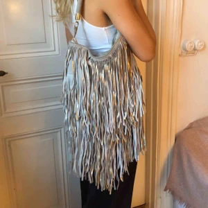  - Hm mockaväska i beige och guld med fransar i fint skick. 