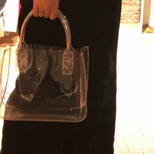  - Genomskinlig väska från Nelly! I väldigt bra skick! Frakt kan tillkomma, kan också mötas upp i Stockholm.