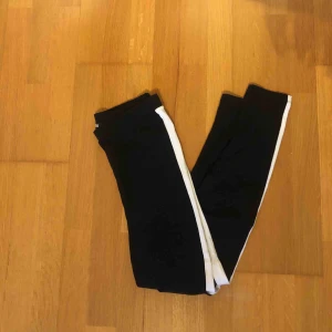  - Svarta leggings med vit rand på sidan.