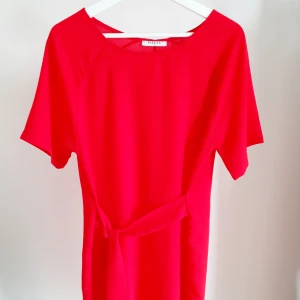 Hallonröd klänning St. M - Midiklänning med knytband i midjan, fin hallonröd färg. Sparsamt använd.