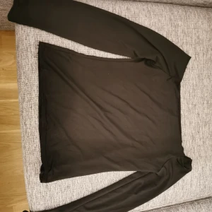 Off shoulder tröja  - Svart glansigt material. Syns dåligt på bilden. Storlek s. 