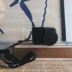 Sony Kamerafodral konstläder  - Superfint kamerafodral i konstläder och så gott som i nyskick. Gjort för Sony Alpa-serien men passar säkerligen till andra kompakta systemkameror. På bilden sitter fodralet på en Sony A6000.   Kan hämtas i centrala sthlm eller skicka mot fraktkostnad. 