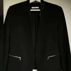 Svart kavaj/blazer - Svart blazer med skin imitation på kragen och guld detaljer. Knappt använd, köparen står för frakten. Kan ta swish!