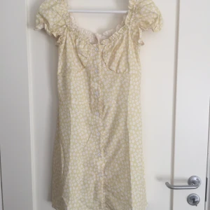 Blommig mini klänning - Gulblommig klänning, använd några få gånger. Funkar både att ha off shoulder eller med ärmarna på axlarna. Köparen betalar frakt 🌼