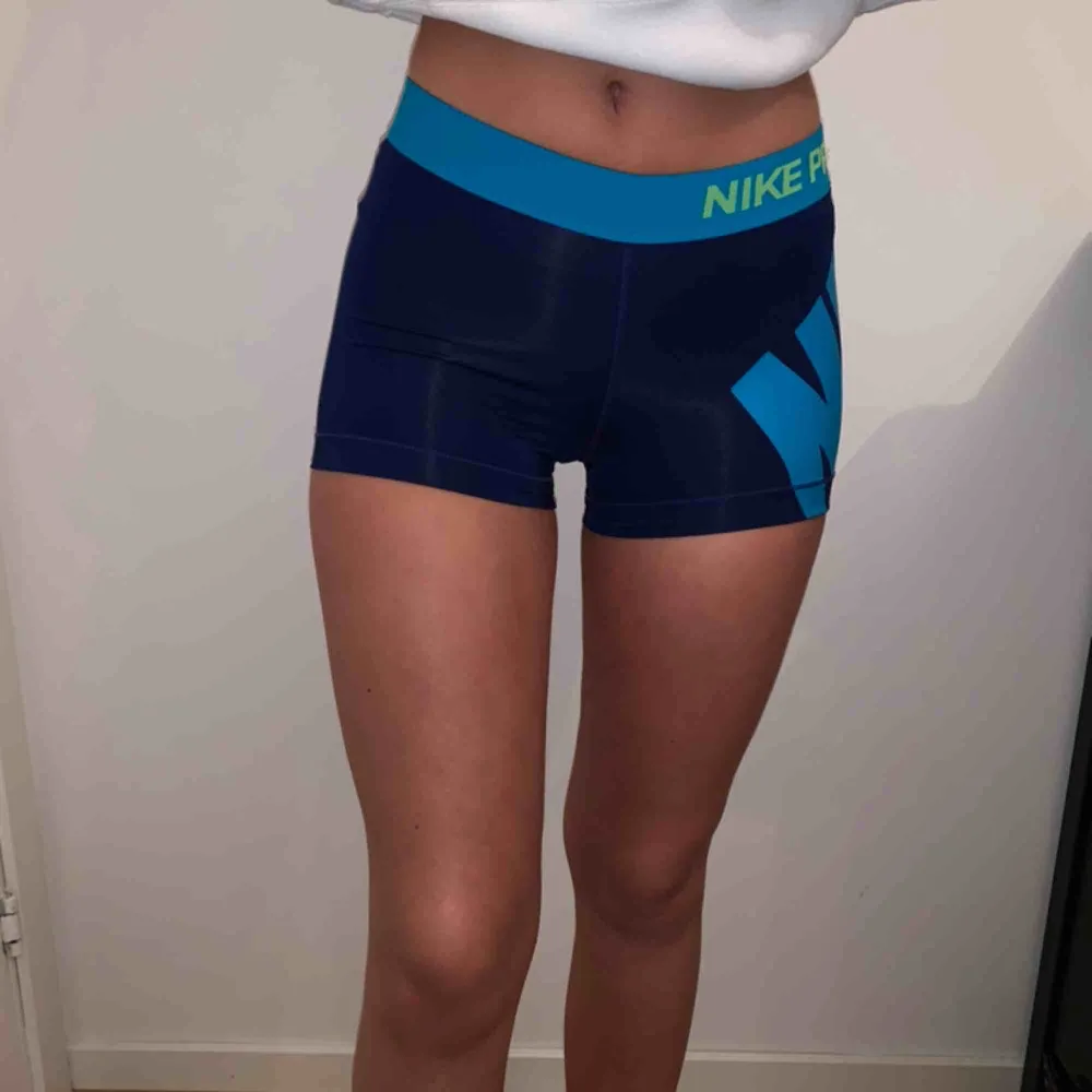 Korta träningsshorts från Nike i mörkblått och detaljer i ljusare blått och grönt. Shorts.