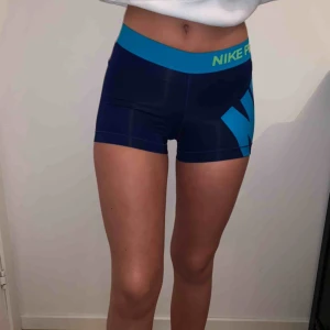  - Korta träningsshorts från Nike i mörkblått och detaljer i ljusare blått och grönt