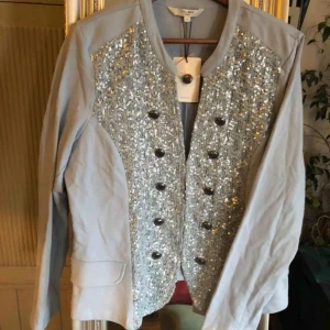  - Grå kofta med paljetter, lapp kvar, strl 42, 100kr 
