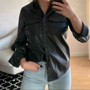  - Linn Ahlborg x NAKD Skjorta i läderimitation. Försluts med knappar. Helt oanvänd (prislapp finns kvar). Köparen står för frakten.