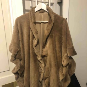  - Mysig fluff poncho/sjal med volang. Perfekt att ta på sig nu när det börjar bli lite kyligt. Hela ponchon har samma färg, det är ljuset från lampan som gör att det ser ut som den skiftar. Aldrig använd prislappen sitter kvar.