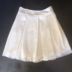  - Tenniskjol i nät, med underkjol i silkesliknande material. Liten dragkedja bak.