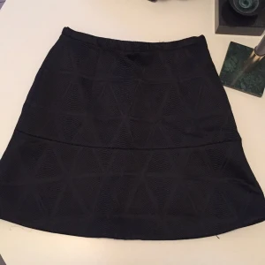  - Svart kjol med struktur från Tiger. Dragkedja baktill.