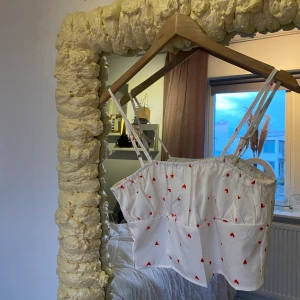 Topp med hjärtan  - Vit topp med hjärtan. Dragkedja finns på sidan så den är lätt att ta på sig. Strethight material, ej genomskinligt!! 