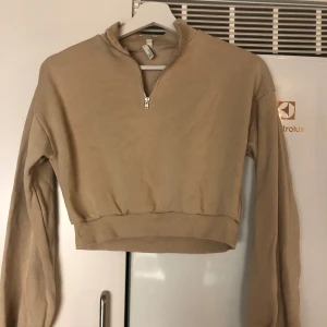 Croppad sweatshirt från nellytrend - Säljer en beige croppad sweatshirt med dragkedja från nellytrend i storlek XS. Köparen står för frakt 79kr.