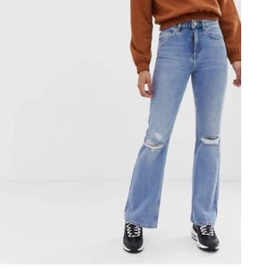 Asos flare/bootcut jeans med hål - Blåa jeans från Asos, högmidjade med hål på knäna. Strl: W25L32. Sitter lite tight på mig runt höften så används inte! Frakt tillkommer🌟 nypris: 480kr