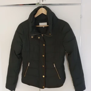 Dunjacka Vila strl M - Mörkgrön dunjacka med fickor, knappar och dragkedja från Vila.