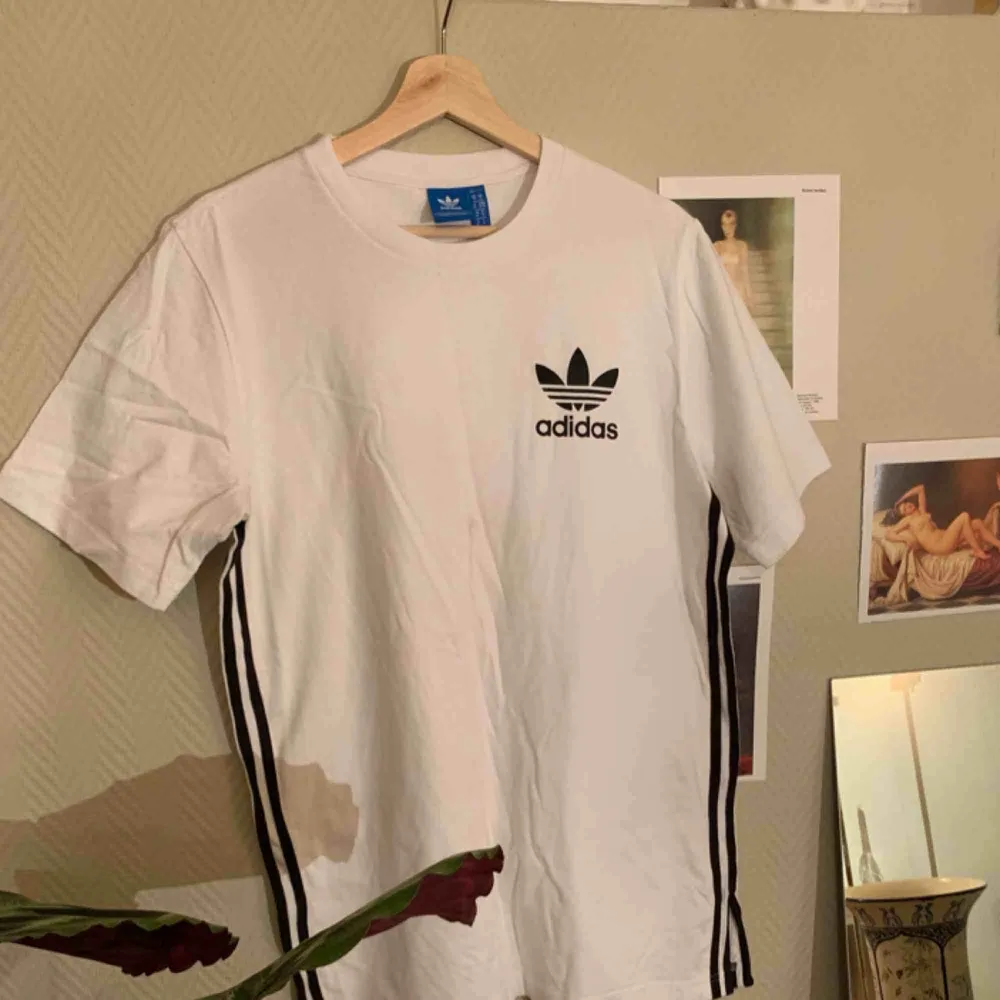 Adidas T-shirt med svarta ränder på sidorna, aldrig använd. (Fraktkostnaden står köparen för). T-shirts.