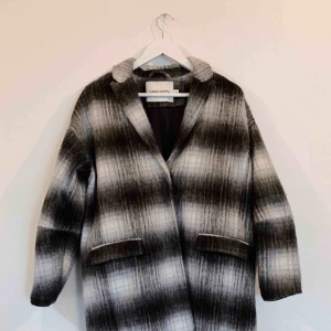  - Varm och mysig kappa från Carin Wester. Knappt använd! Svart/grå/vit med två fickor.